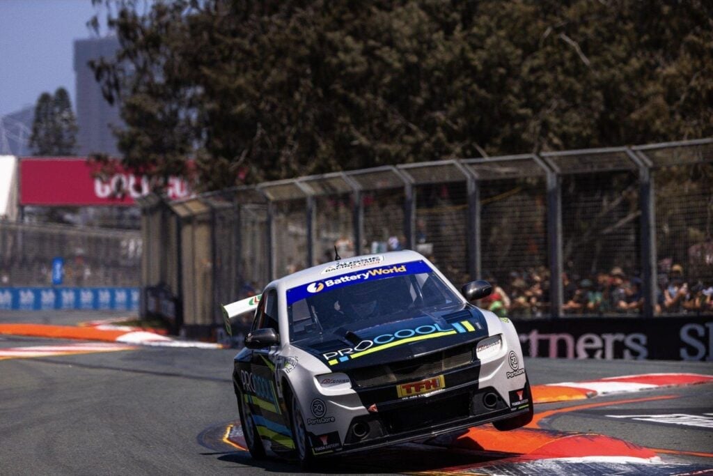 A Pro Cool sponsored race car leaning sharply while navigating a turn on a racetrack.